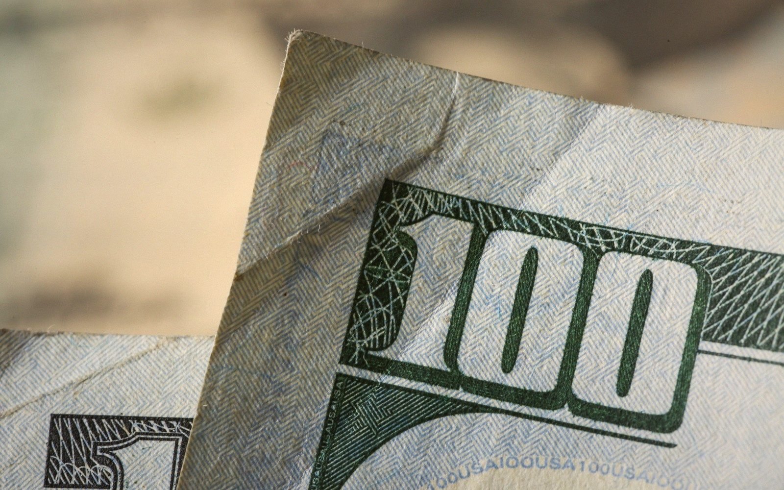 Close-up of folded US $100 and $50 bills showing corner denomination numerals