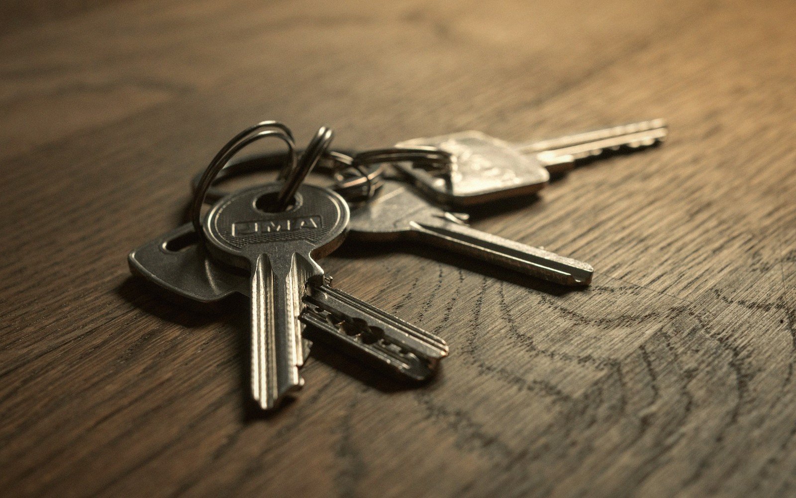 A bundle of metal keys on a ring resting on a wooden table